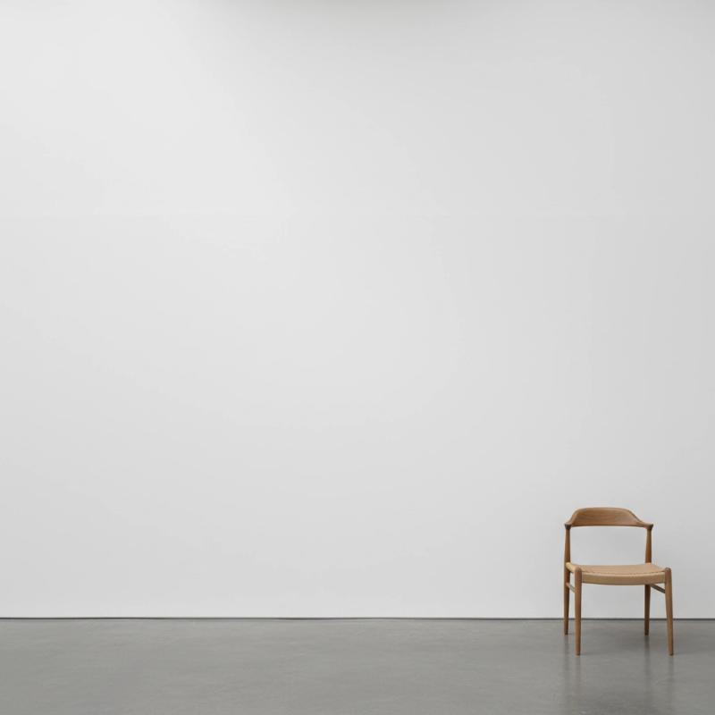 Minimalist white-cube gallery with a wooden chair