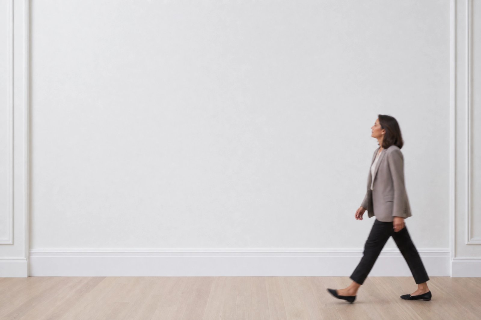Wall art mockup: White gallery with a person walking and wooden floor, with a person