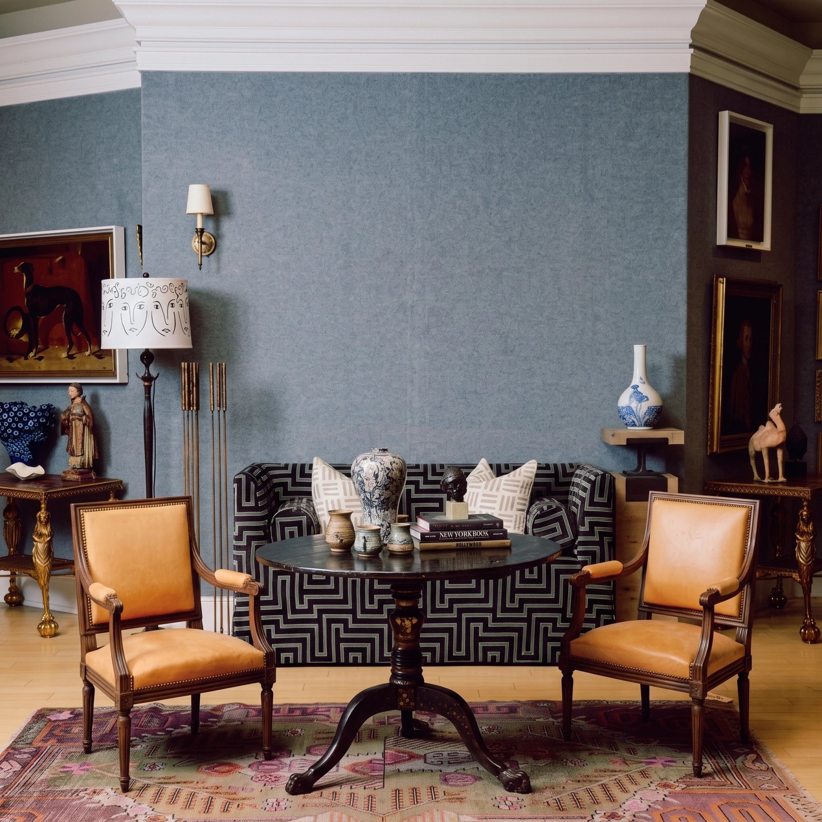 Wall art mockup: Eclectic sitting room with patterned sofa and antique furniture, with a coffee table and lamps