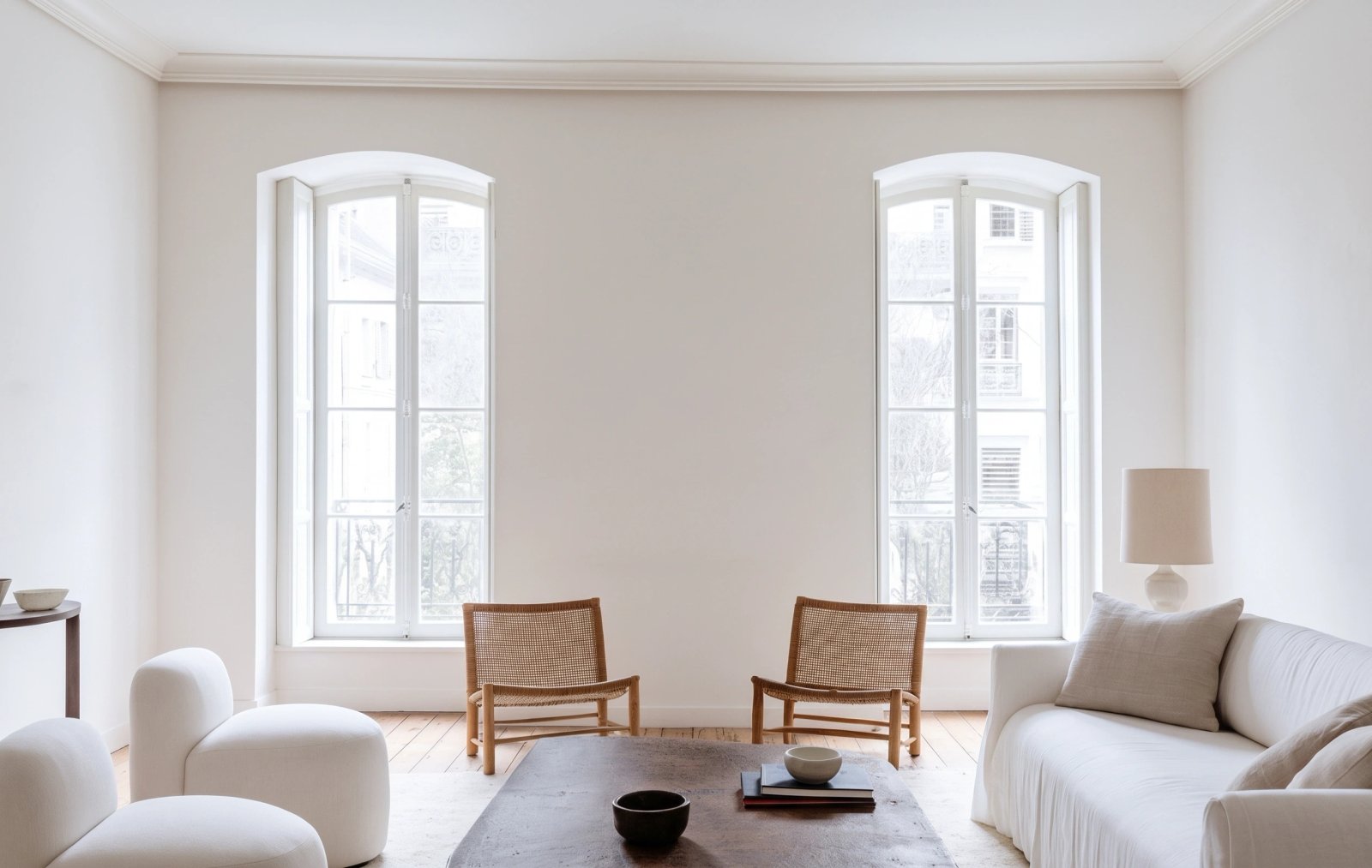 Wall art mockup: Contemporary living room with a white sofa and cane chairs, with a sofa, lamps and a window